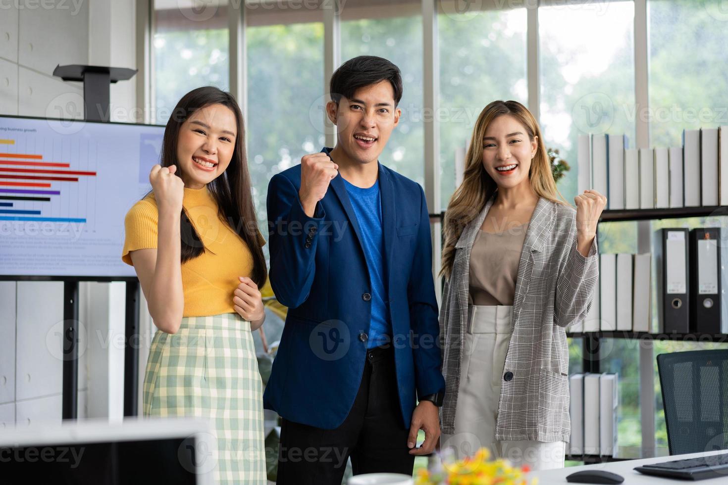 grupo de jóvenes empresarios asiáticos personas creativas mirando la cámara y emocionados por el éxito del proyecto, trabajando juntos en la oficina. El equipo comercial de Stratup discute y comparte ideas para nuevos proyectos. foto