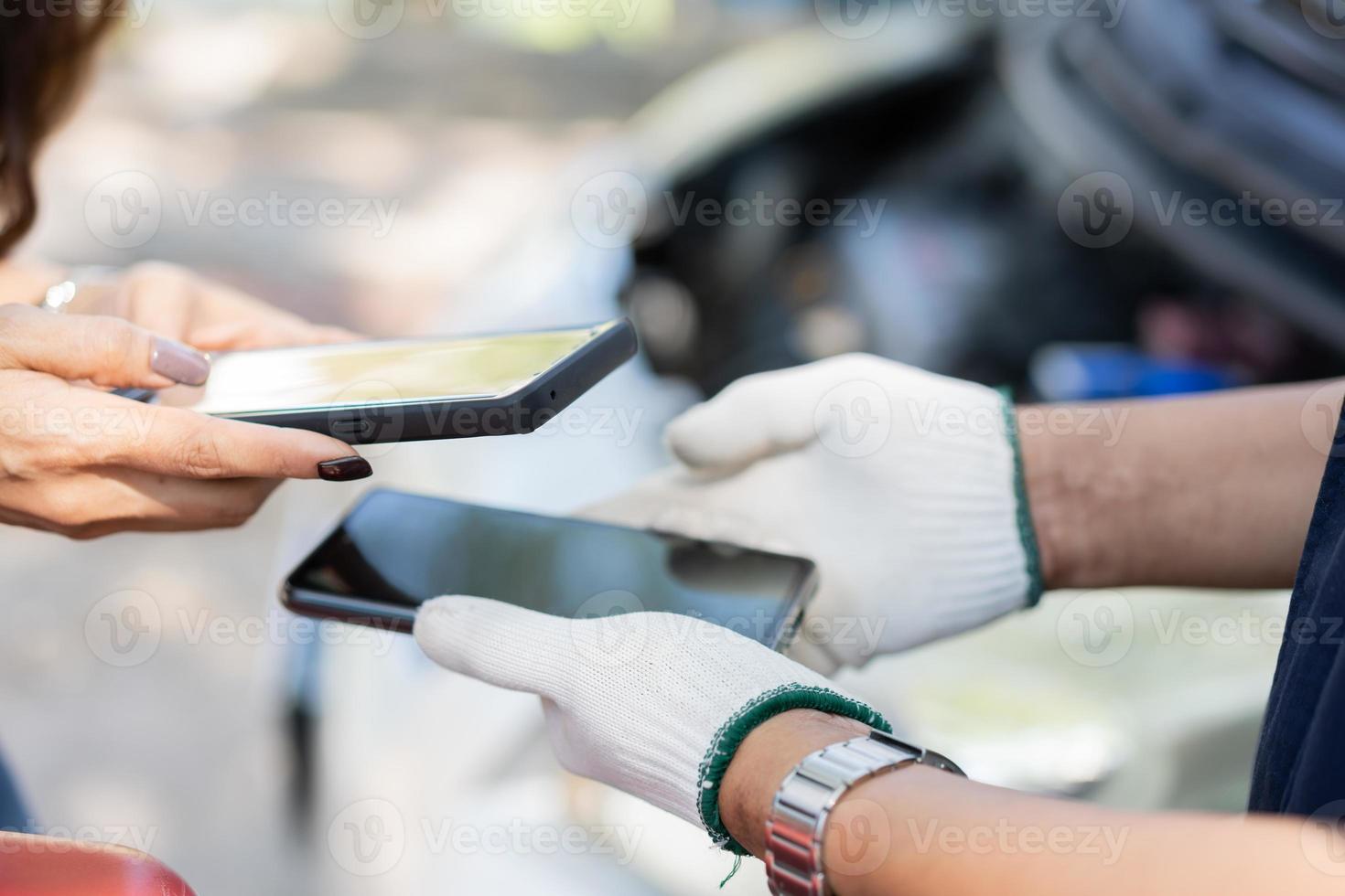 Asian women get contact numbers from Asian male auto mechanics after fixing the car engine problem and QR code scan to pay for fixing vehicle service. Car repair, and maintenance concept. photo