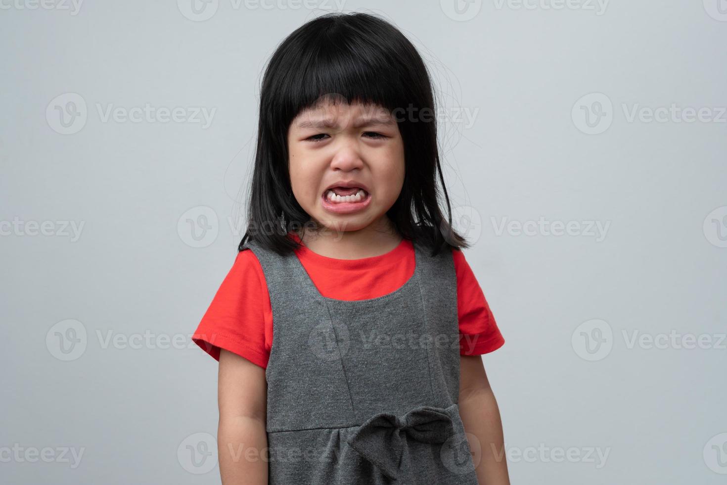 Portrait of Asian angry, sad and cry little girl on white isolated background, The emotion of a child when tantrum and mad, expression grumpy emotion. Kid emotional control concept photo