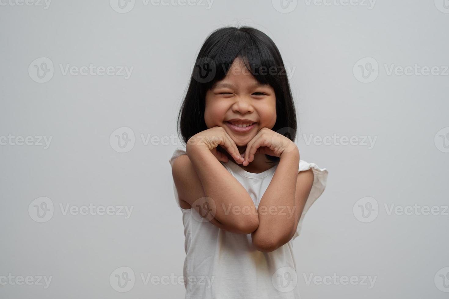 retrato de niña asiática feliz y divertida sobre fondo blanco, un niño mirando a la cámara. niño preescolar soñando llenarse de energía sintiéndose saludable y buen concepto foto