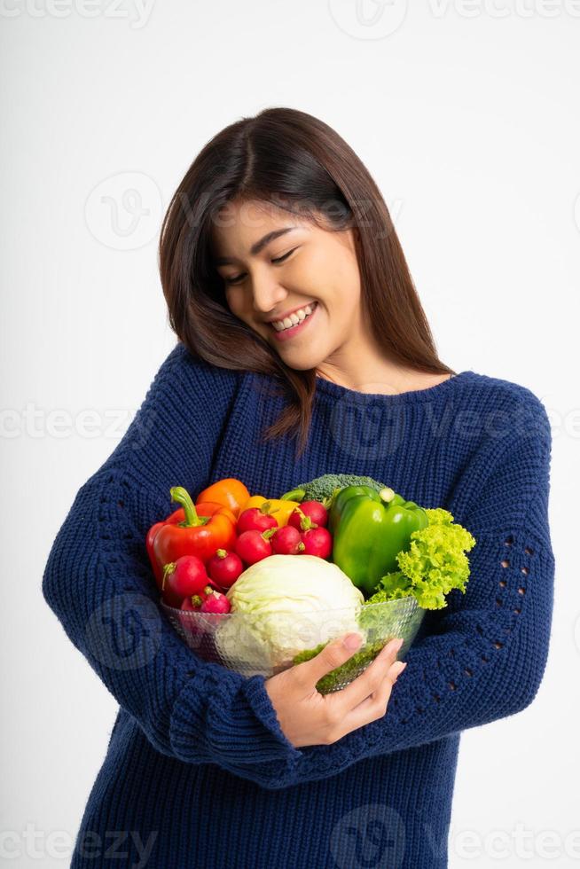 retrato de una hermosa mujer asiática sonriente sosteniendo un tazón lleno de verduras orgánicas frescas aisladas de fondo blanco, concepto de nutrición alimentaria saludable, concepto de nutrición alimentaria saludable, vegetariana foto