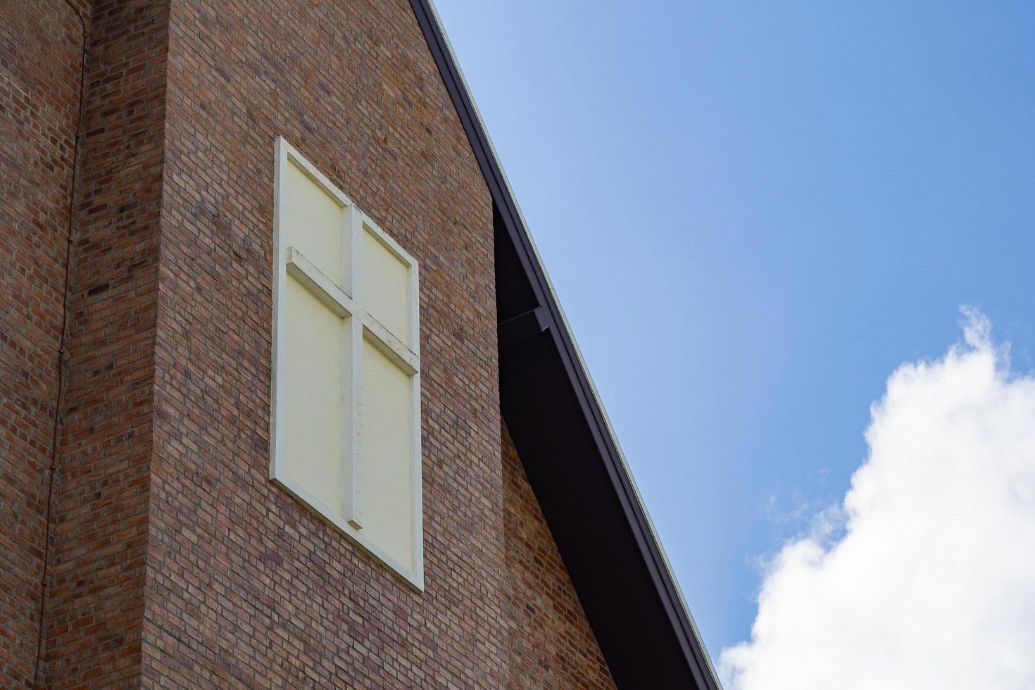 The cross in the wall of Church with blue sky and white clouds background photo