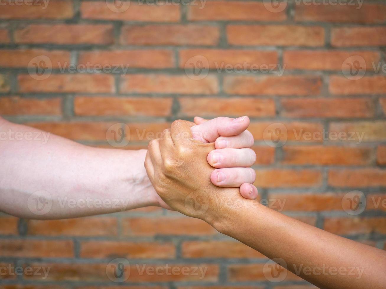 Close-up image of shaking hands between man and woman with brick background photo