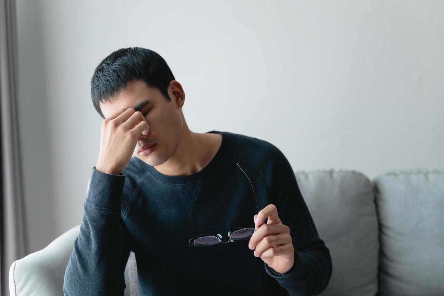 stressed man take off glasses massage eyes feel fatigue suffering from headache, exhausted man having eyestrain or astigmatism with overwork. photo