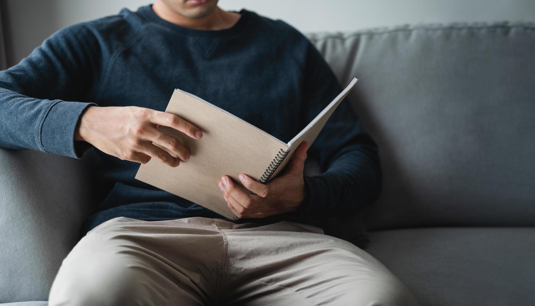 Man reading the notebook sitting on the sofa at home. photo