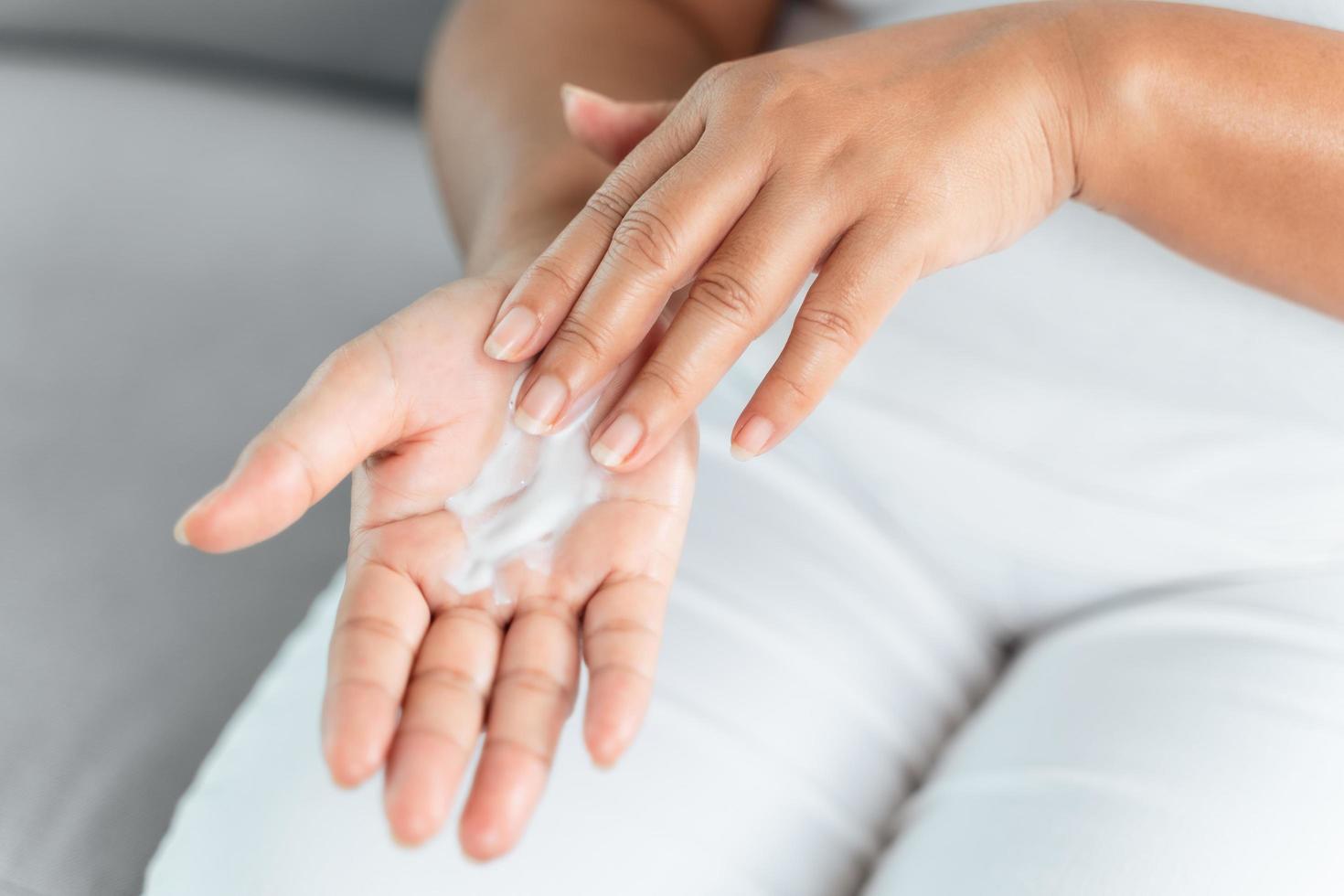 mujer aplicando crema hidratante de loción corporal en sus manos. foto