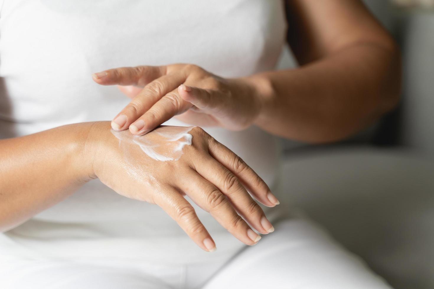 Woman applying body lotion moisturizer on her hands. photo
