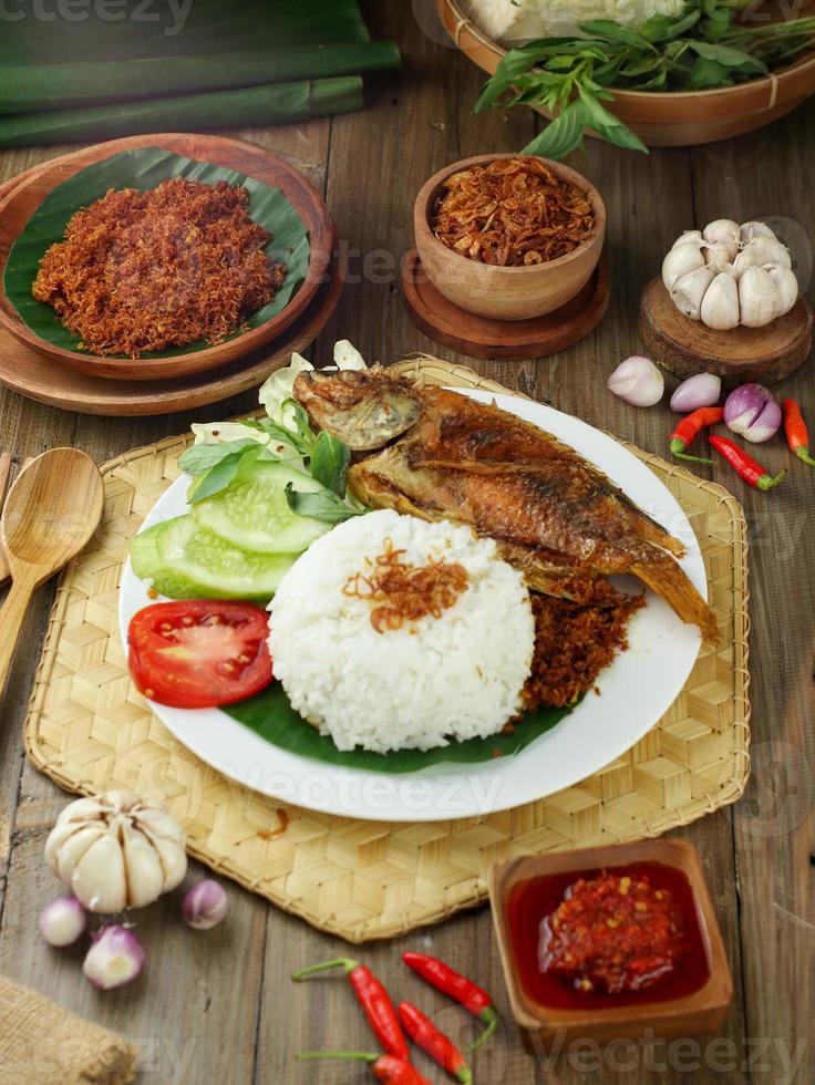 Crispy fried fish served with rice, vegetables and chili photo