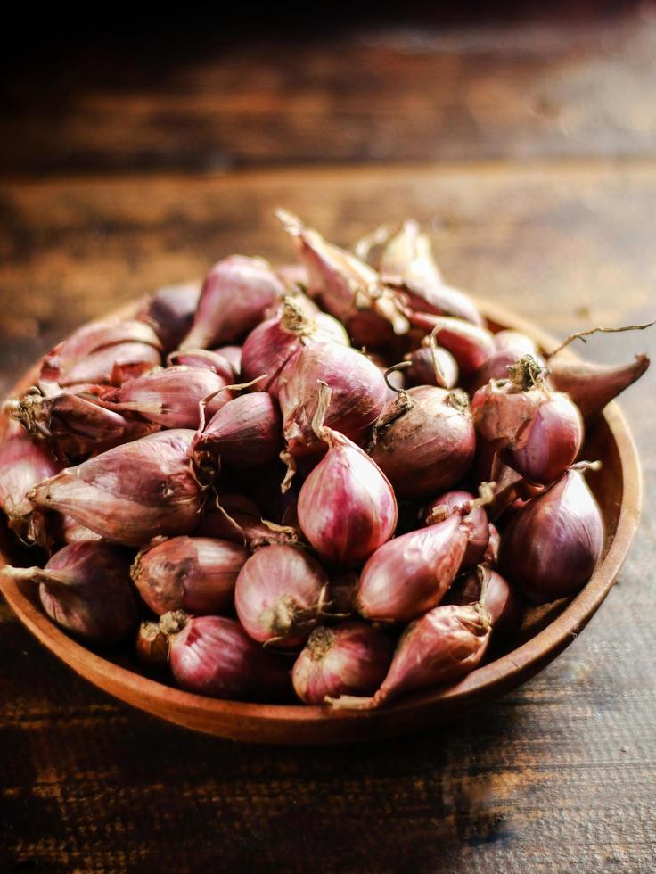 red onion or Shallots. shallots on wooden plate with . Selected focus. Concept of spices in healthy cooking photo