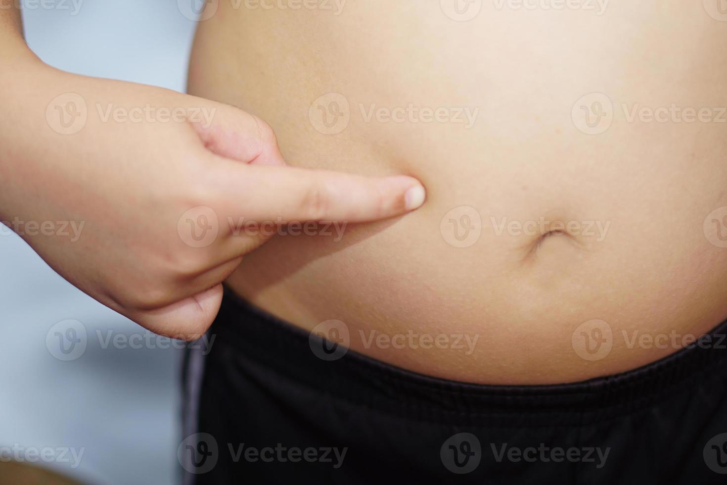 Fat boy, put the index finger on the belly himself. Health, treatment and exercise concept. photo