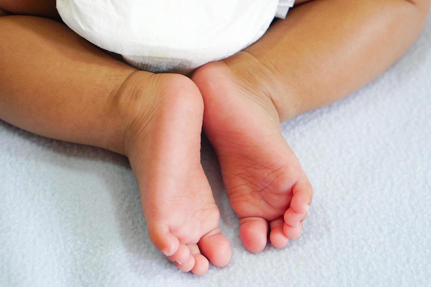 pequeños pies de bebé o pies de bebé recién nacido mientras se acuesta en una acogedora tela azul cielo con amor, cuidado, aliento, empatía, encantador, lindo. foto