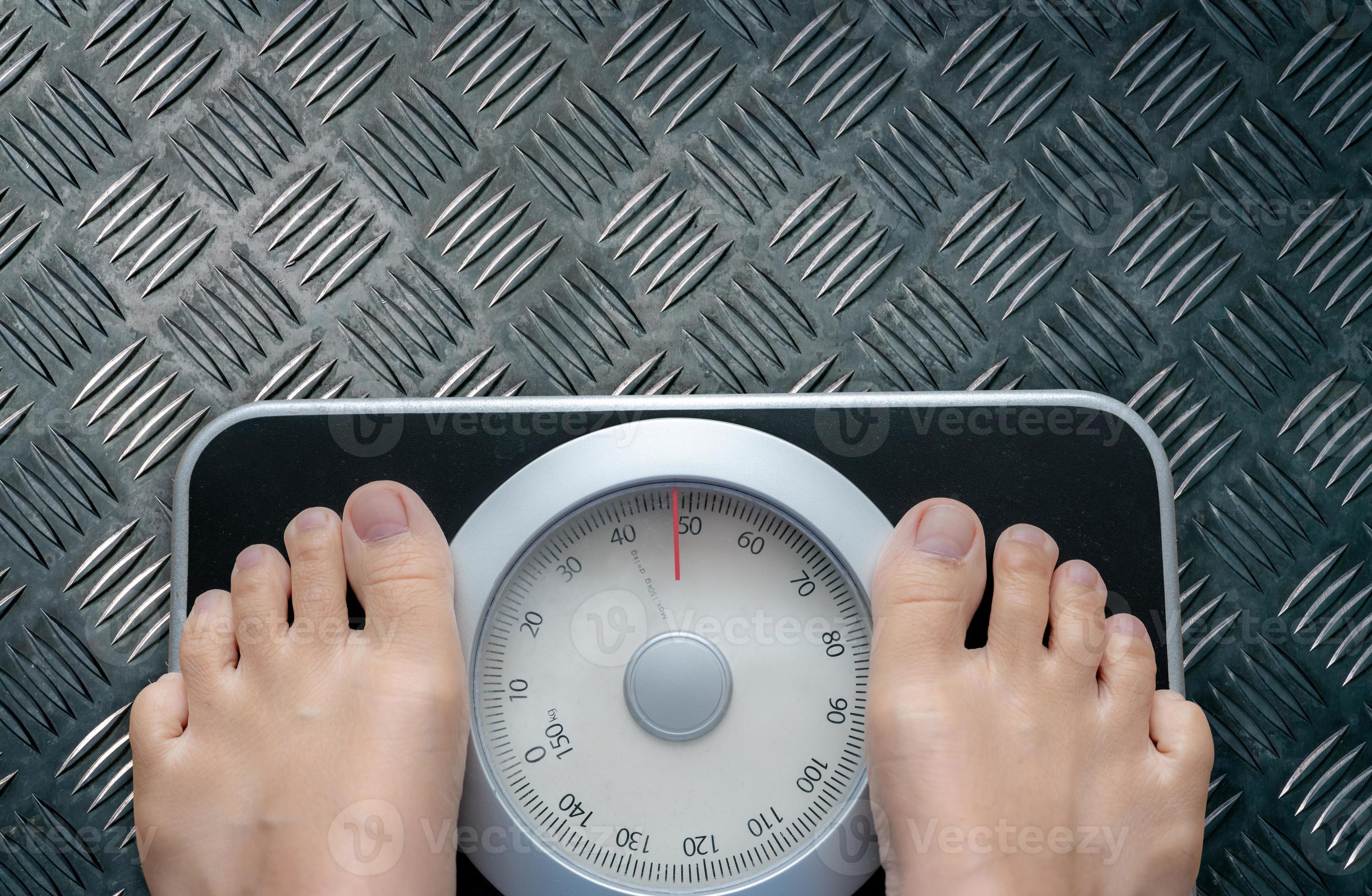 Top view of feet on weighing scale. Women weigh on a weight balance scale  after diet control. Healthy body weight. Weight and fat loss concept. Weight  measure machine. Body Mass Index or