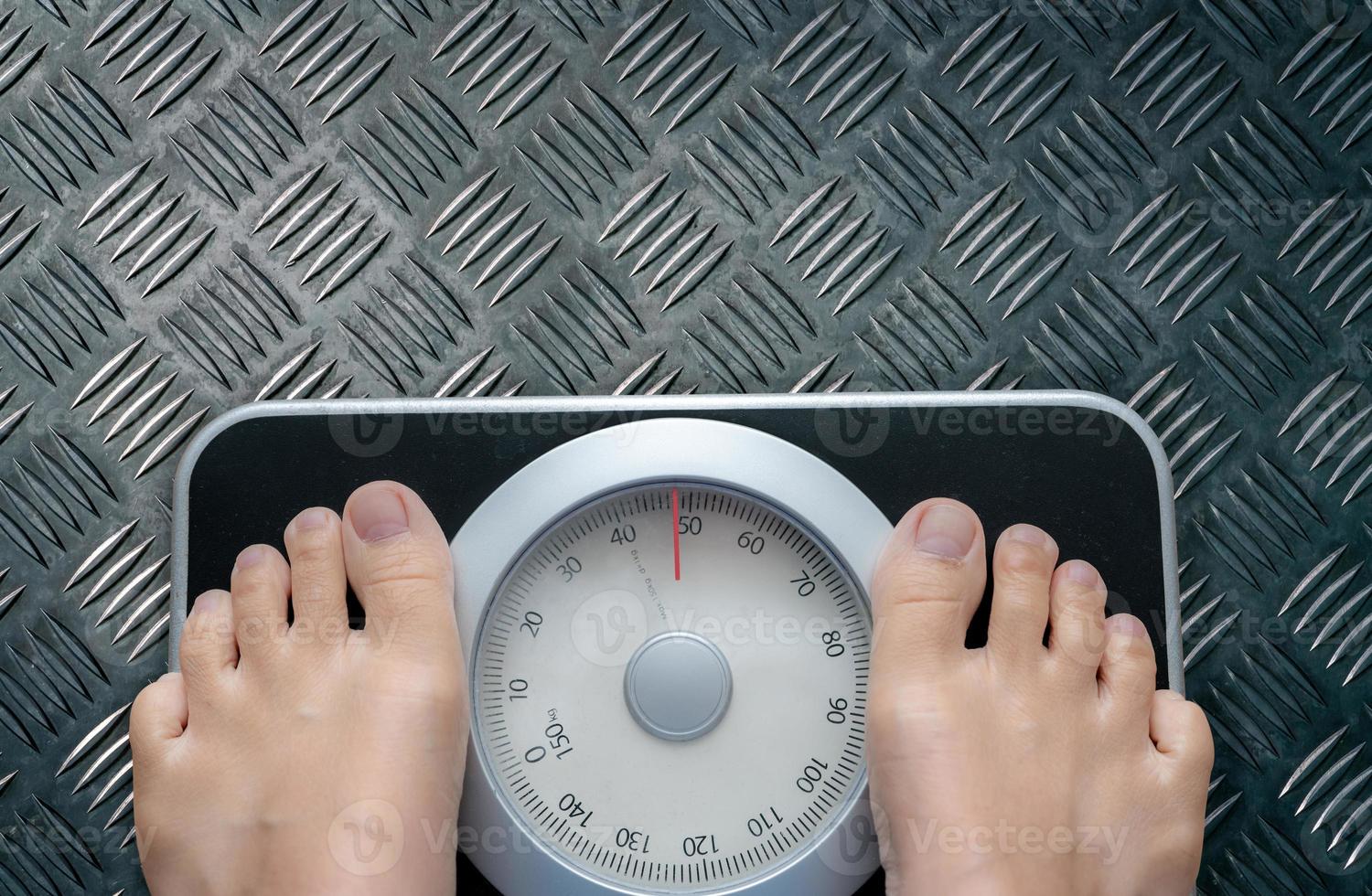 Top view of feet on weighing scale. Women weigh on a weight balance scale after diet control. Healthy body weight. Weight and fat loss concept. Weight measure machine. Body Mass Index or BMI concept. photo