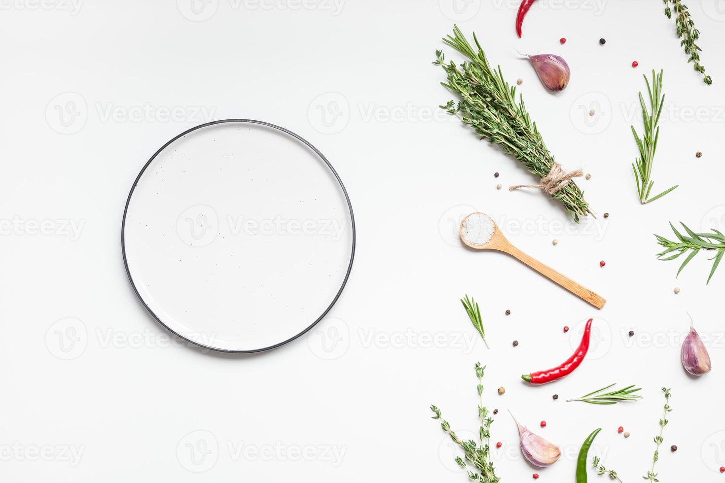 Empty plate with greens herbs and spices around photo