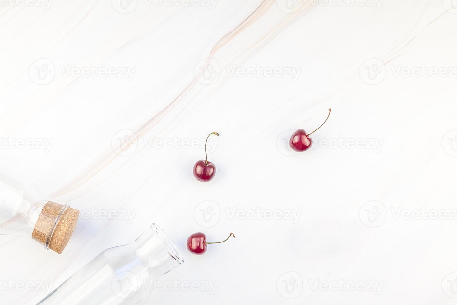 Glass bottles and ripe cherries photo