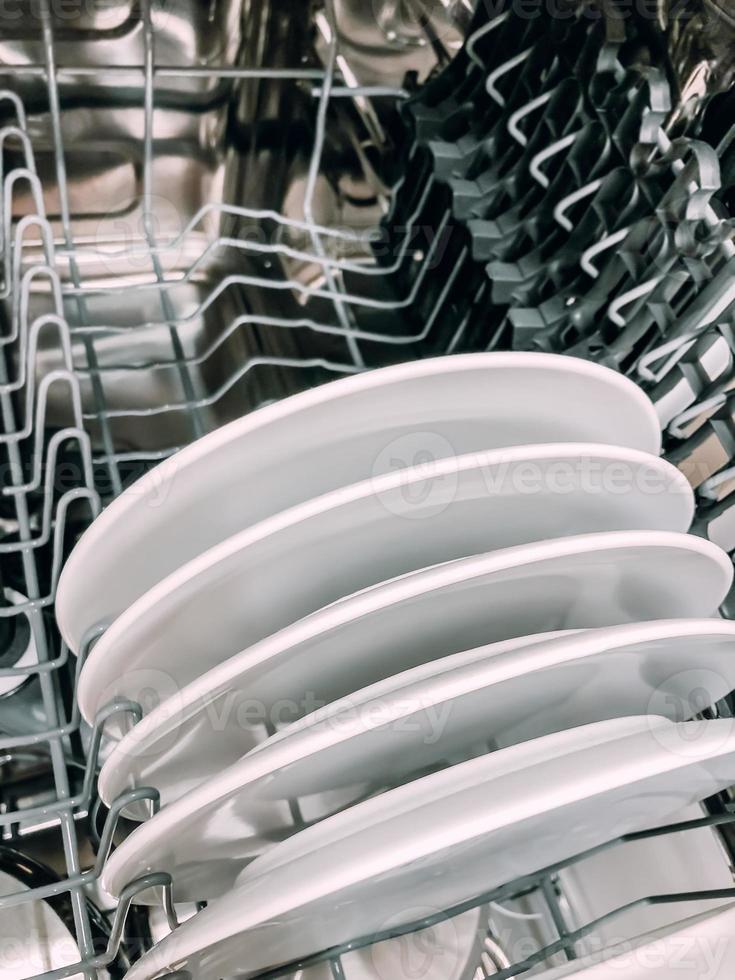Open dishwasher machine with white clean dishes photo