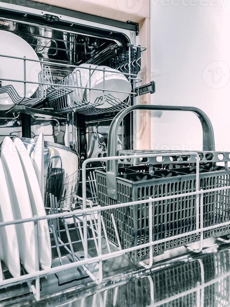 Open dishwasher machine with white clean dishes photo