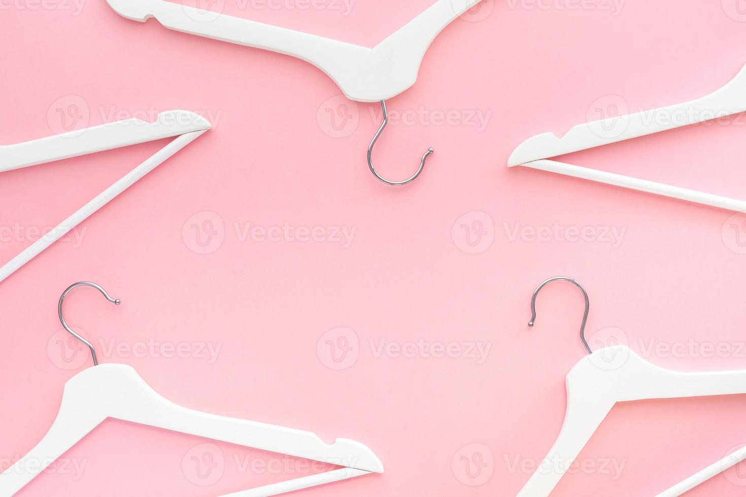 White hangers on pastel pink background photo