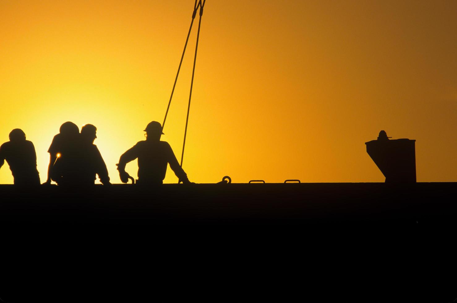 trabajadores portuarios en carguero en silueta foto