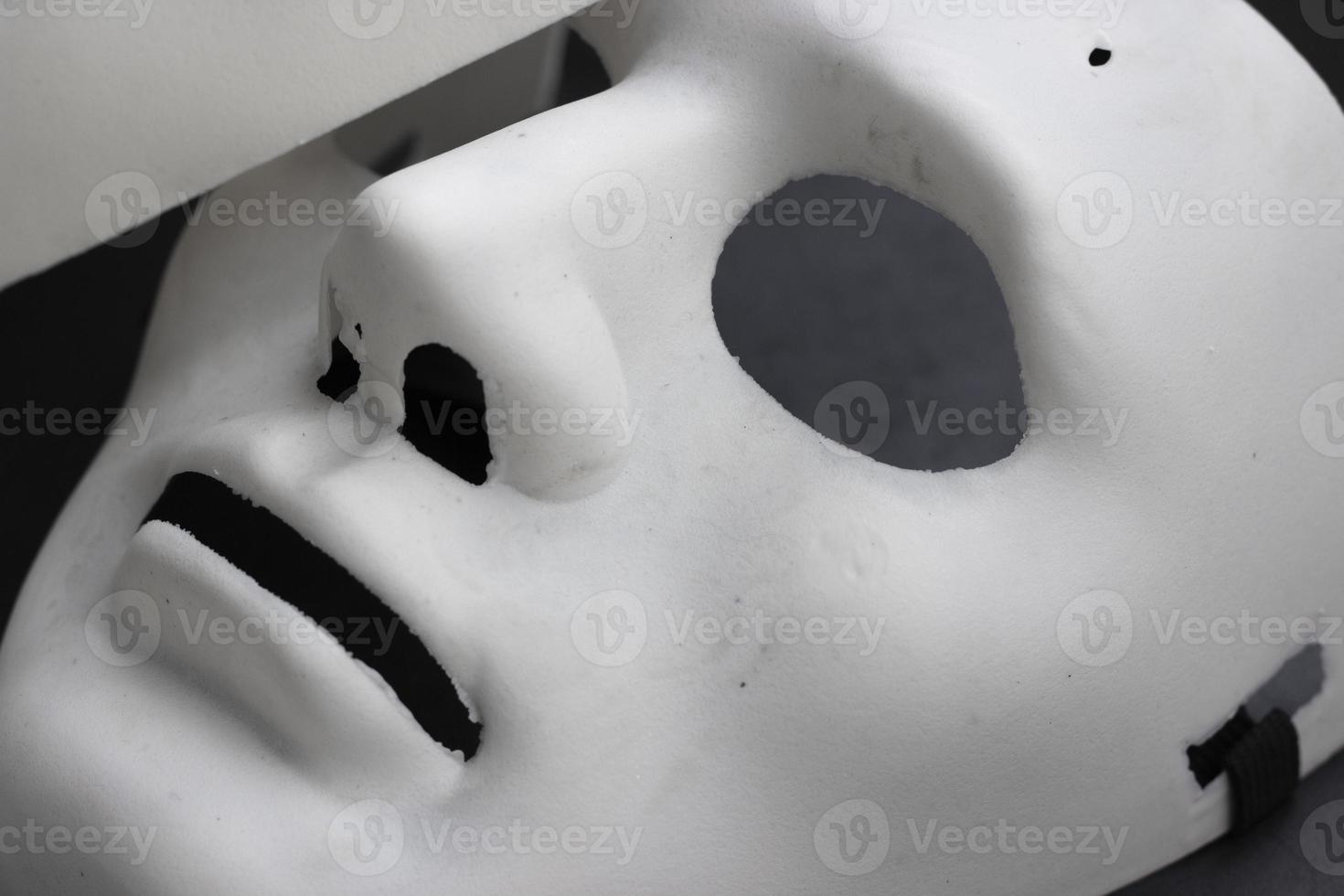 máscara facial de carnaval de mentira blanca, primer plano, foto horizontal sobre fondo oscuro. máscara plástica de teatro, accesorios para ocultar la cara, emociones neutras. elemento de diseño