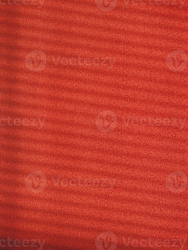 Red textured wall with blinds shadows, warm colors, vertical photo. Decorative background for design, ornament from parallel lines, backdrop or wallpaper photo