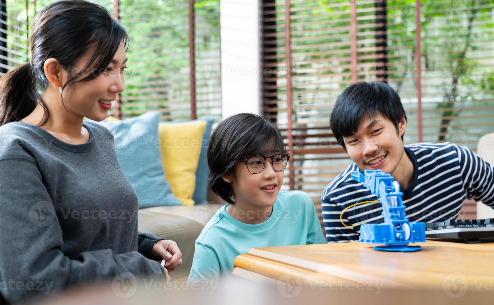 Asian kids program robotic cranes with laptops to learn about technology, math, engineering. programming and coding at home photo