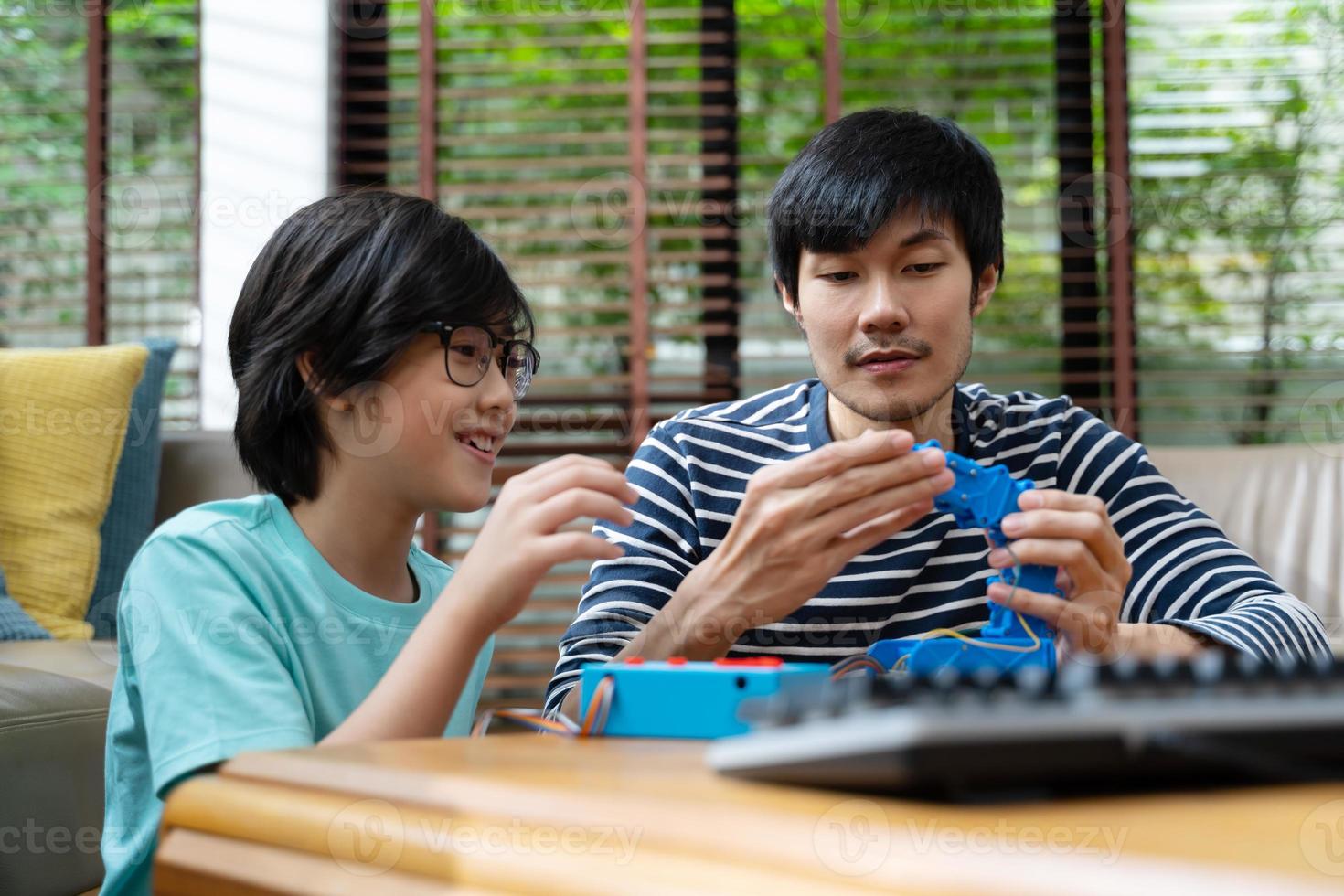 Asian kids program robotic cranes with laptops to learn about technology, math, engineering. programming and coding at home photo