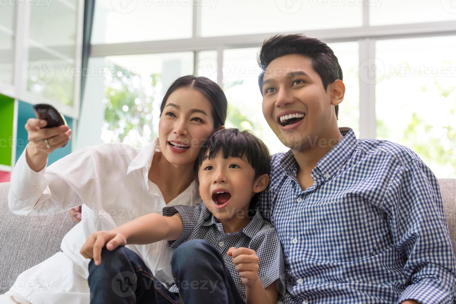 Asian family watching tv together on sofa in living room. family and home photo