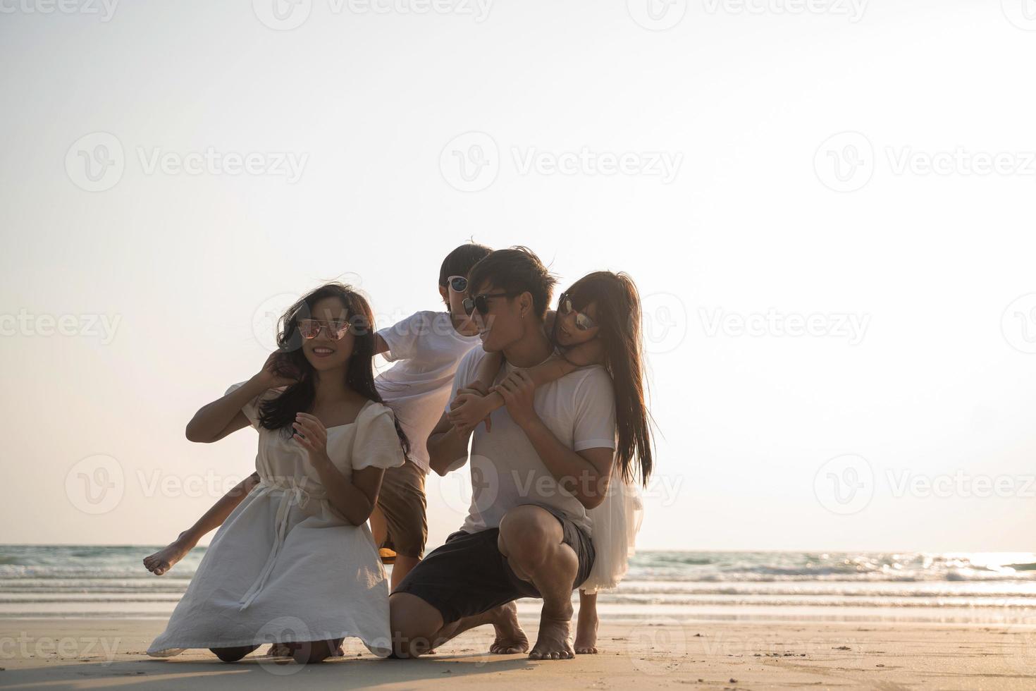 familia asiática caminando en la playa con niños felices vacaciones concepto foto