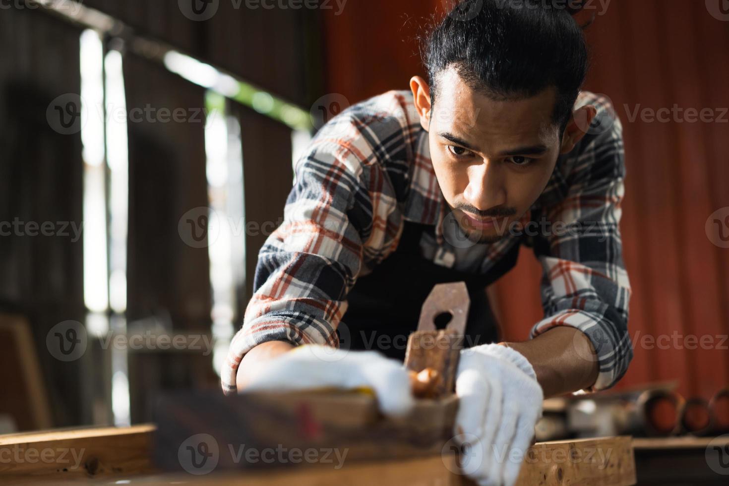 Young Asian man Carpenter working in woodcraft carpentry workshop. photo