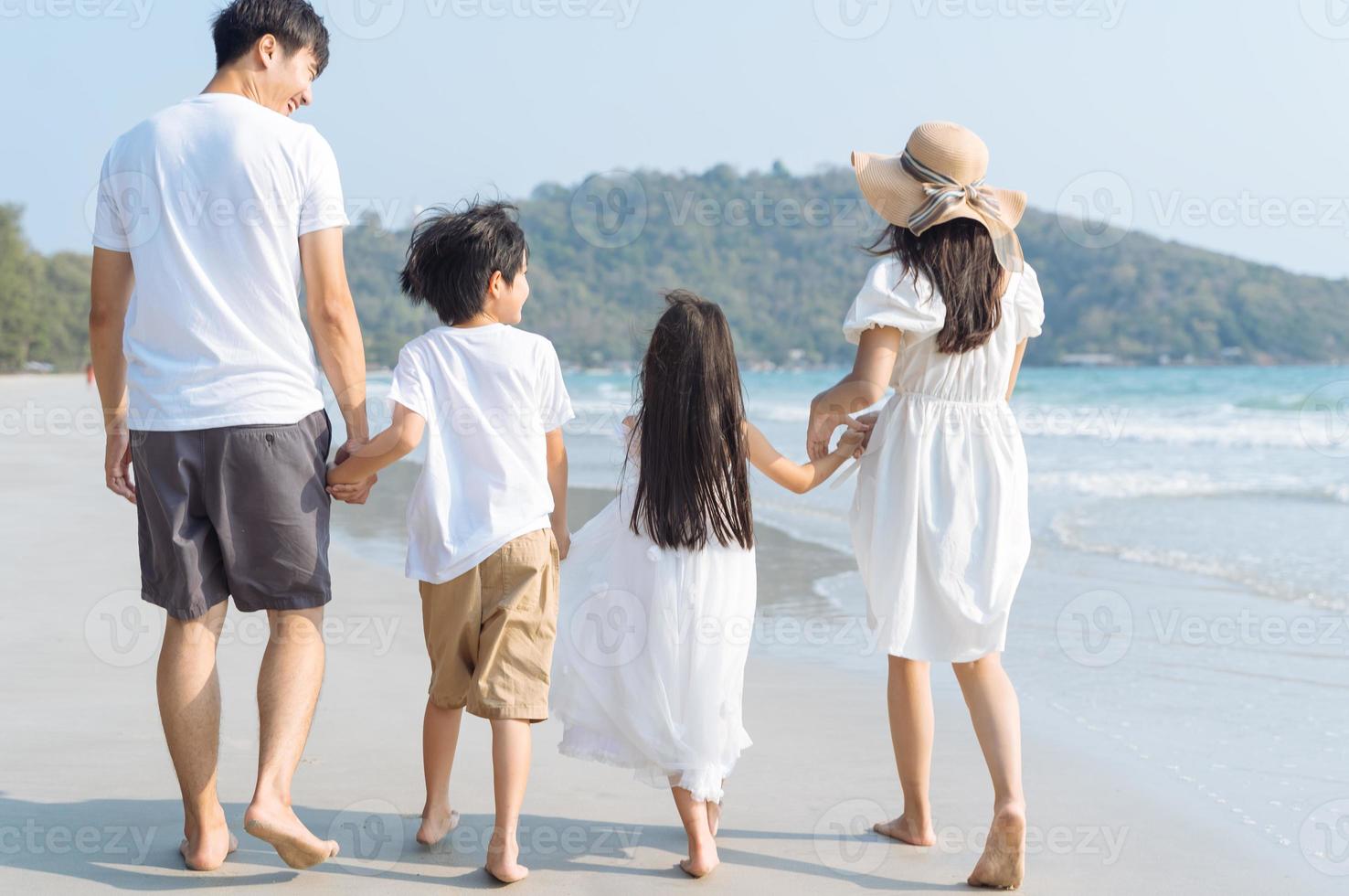 familia asiática caminando en la playa con niños felices vacaciones concepto foto