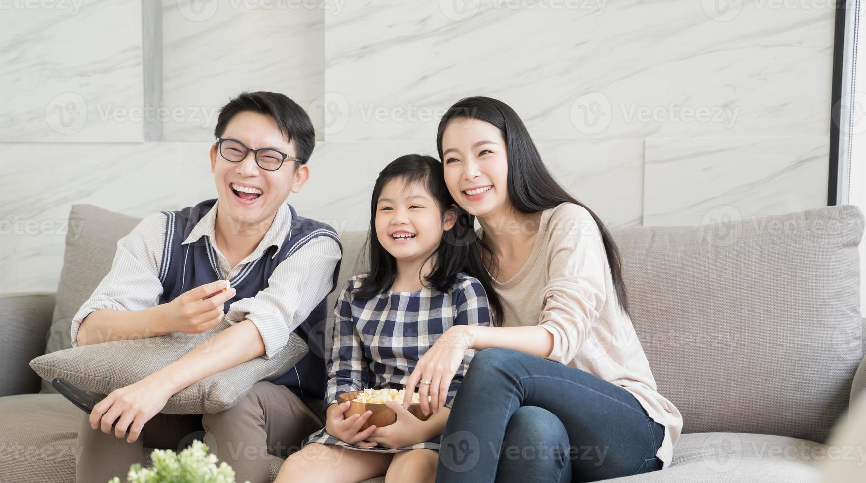 happy asian family watching tv together on sofa in living room. family and home concept photo