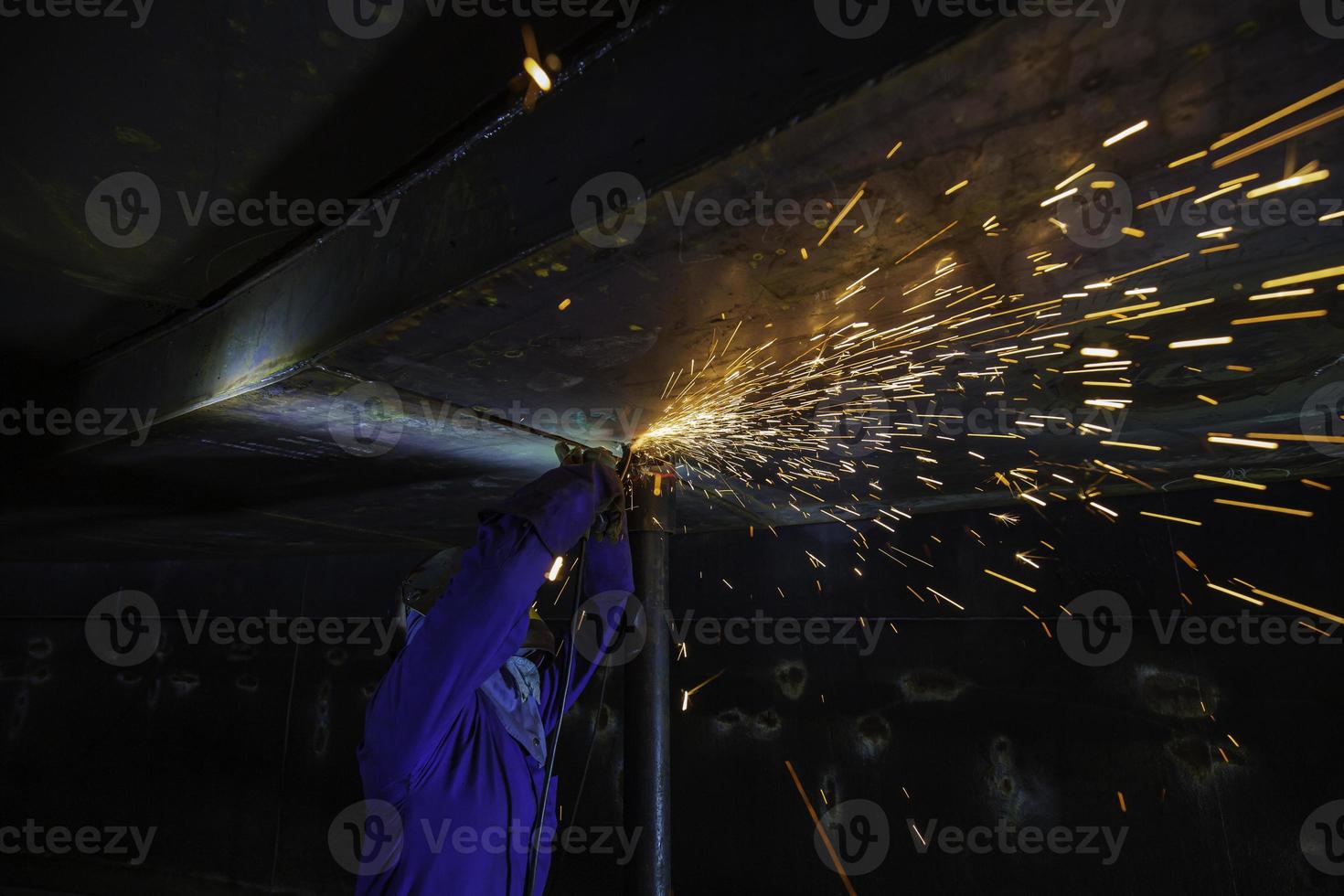 Male worker  grinding on steel plate with flash of sparks close up wear protective gloves photo