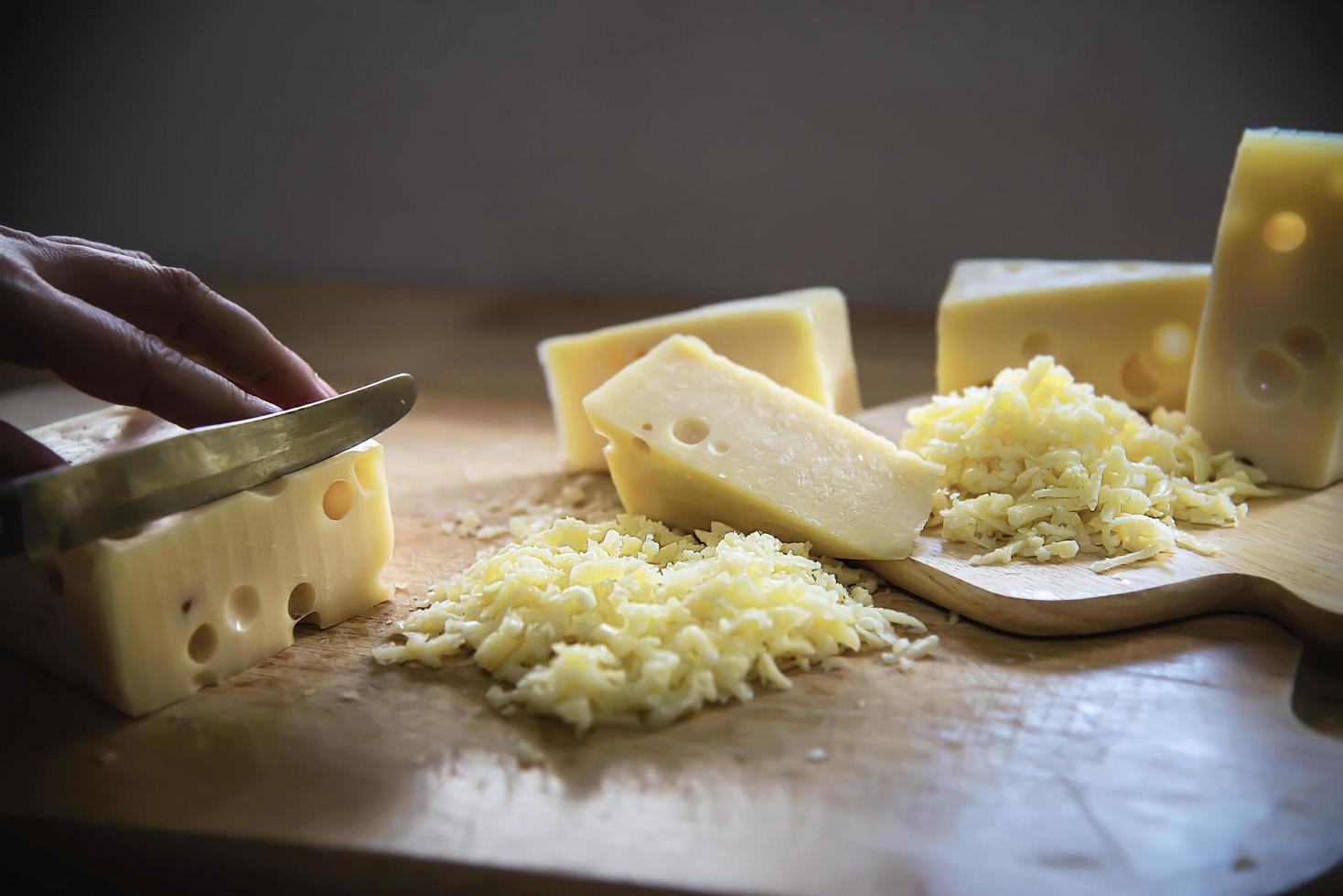 Woman preparing cheese for cook using cheese grater in the kitchen - people making food with cheese concept photo