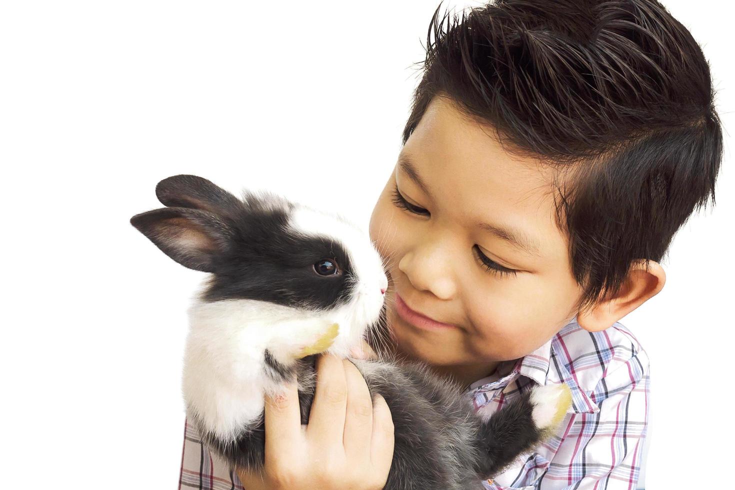 niño asiático jugando con un encantador conejo bebé aislado sobre blanco foto