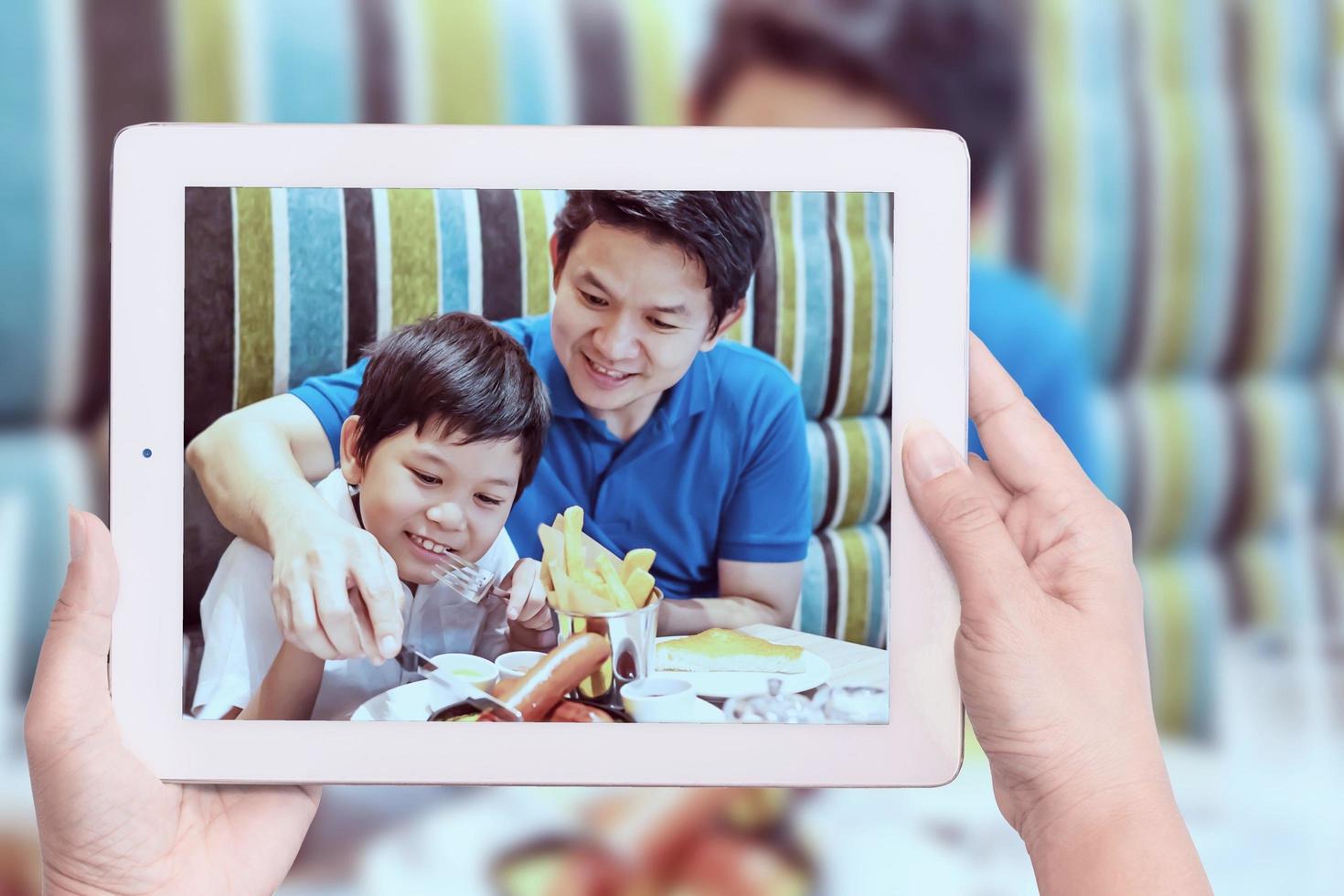 mamá toma una foto de un niño asiático y papá comiendo papas fritas felizmente - niño con comida chatarra poco saludable y concepto de familia feliz