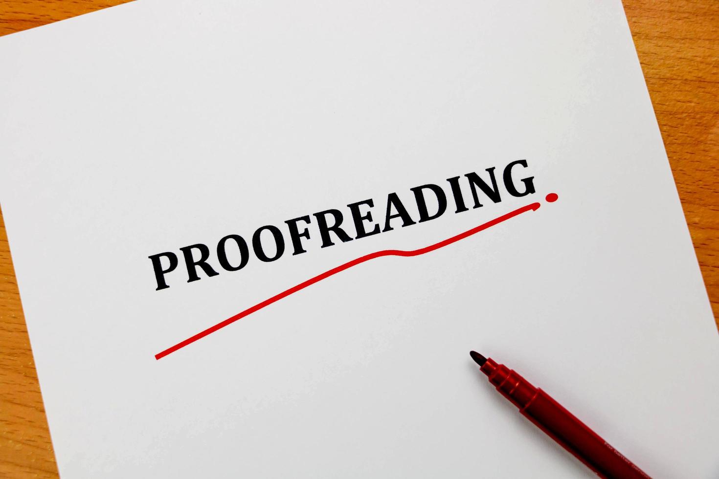 proofreading word on white sheet with red pen photo