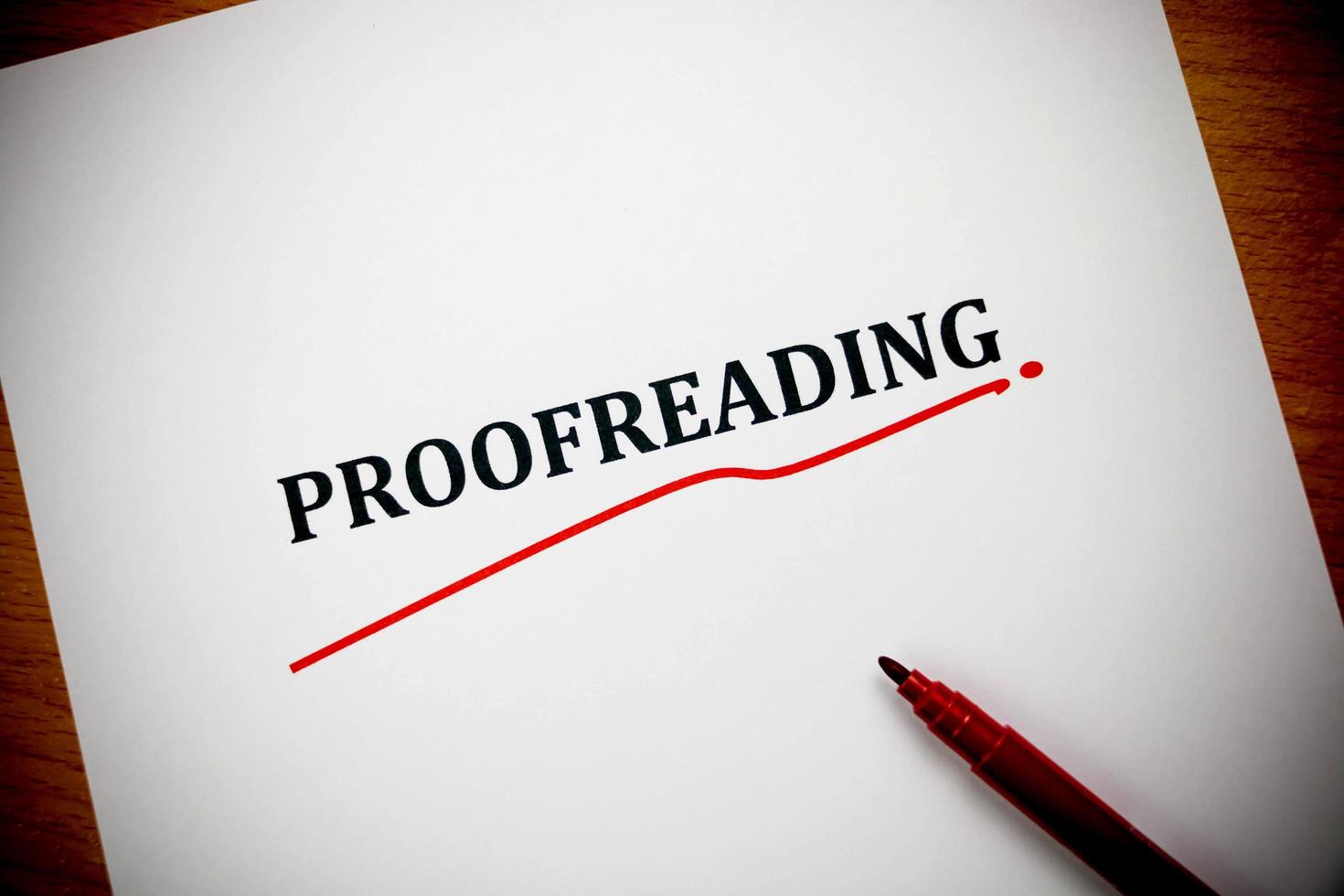 proofreading word on white sheet with red pen photo