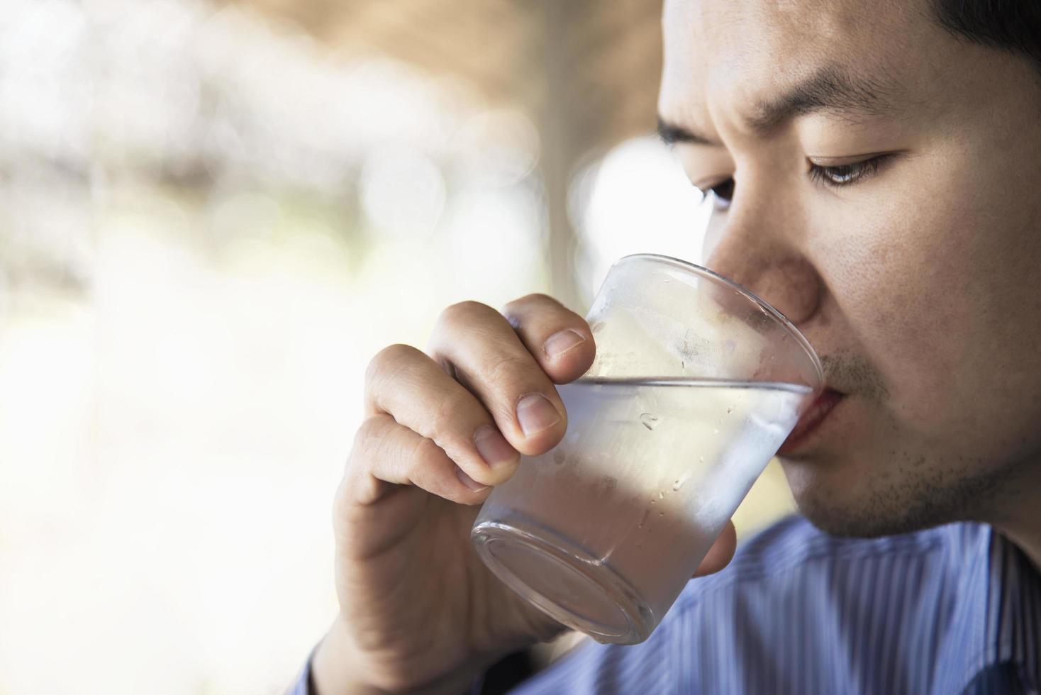 el hombre bebe agua fresca y pura en un vaso foto