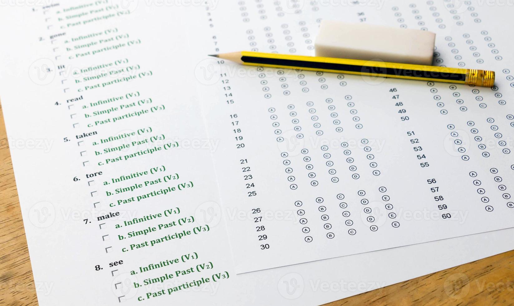 english exercise and answer sheet on brown wooden table photo