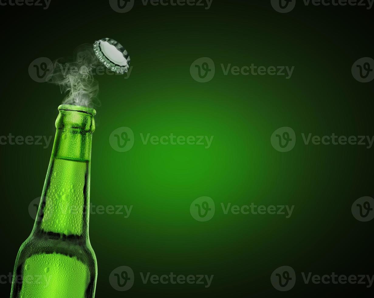 cold wet open beer bottle with smoke on green background photo