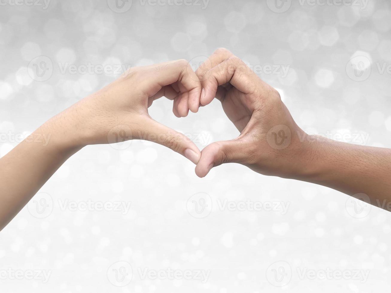 pareja haciendo forma de corazón con la mano en el brillante fondo bokeh foto