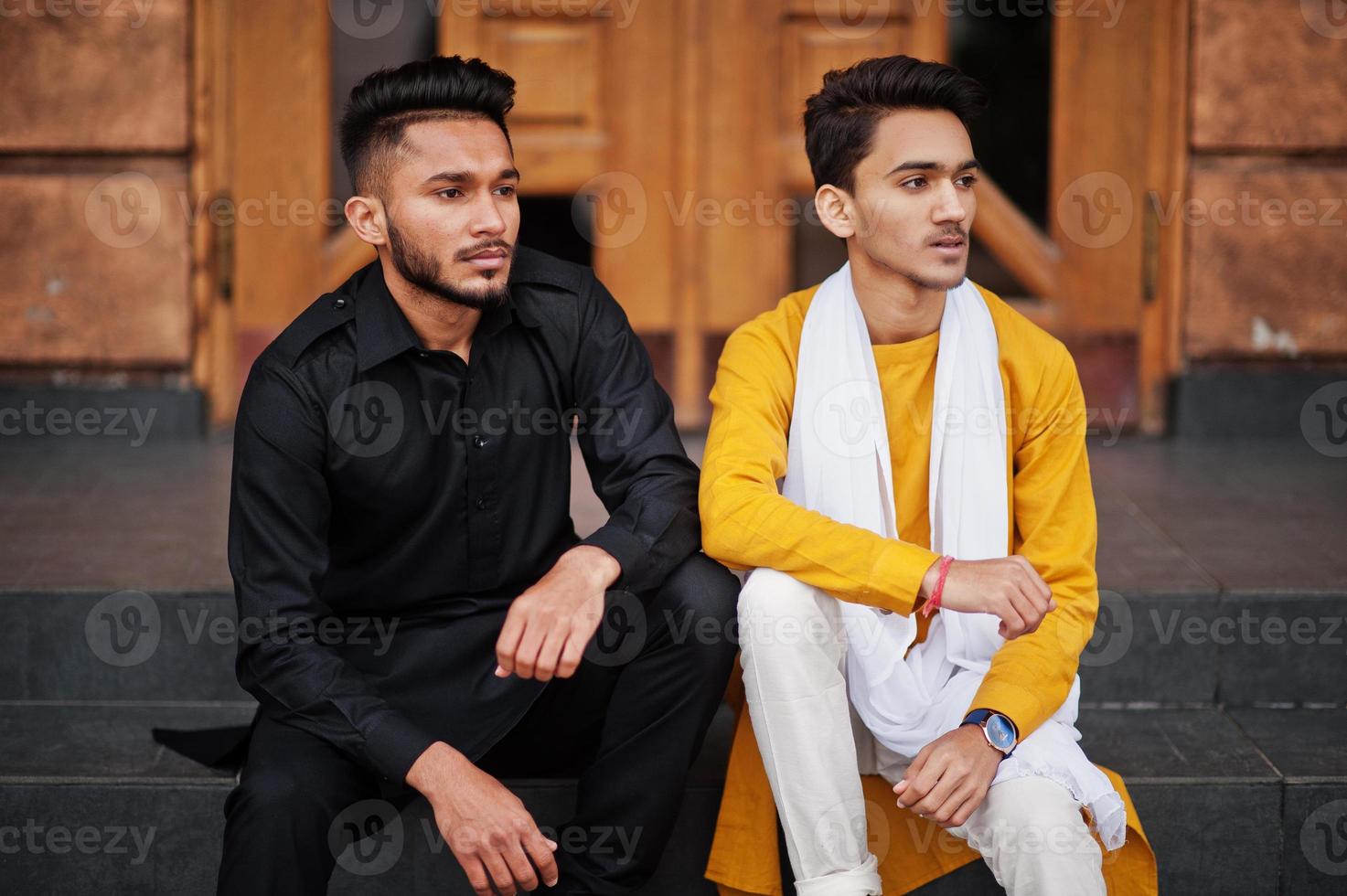 Two indian stylish mans friends in traditional clothes posed outdoor and sitting on stairs. photo