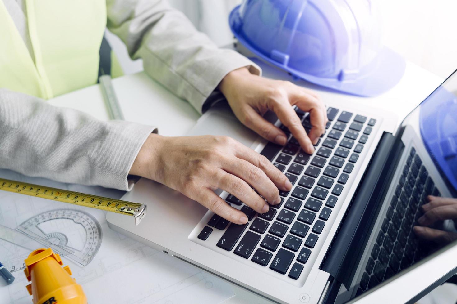 Two colleagues discussing data working and tablet, laptop with on on architectural project at construction site at desk in office photo