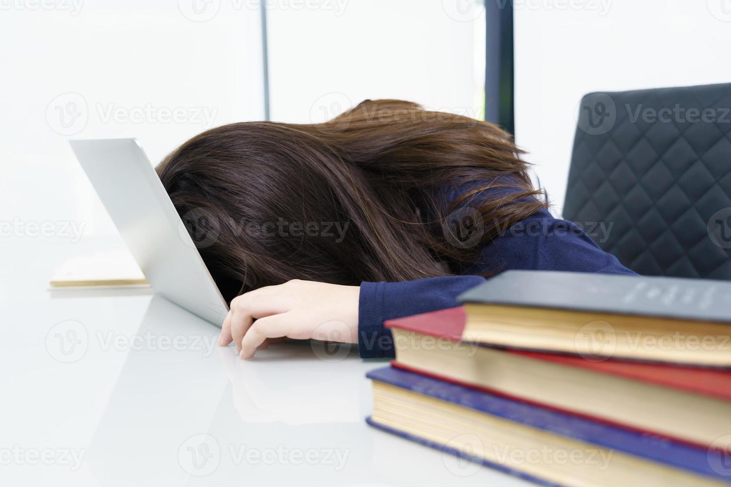 Young woman long hair fall asleep on desk with laptop photo