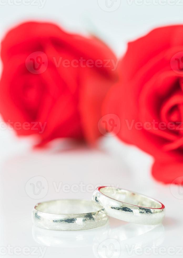 Red rose and wedding ring on white photo