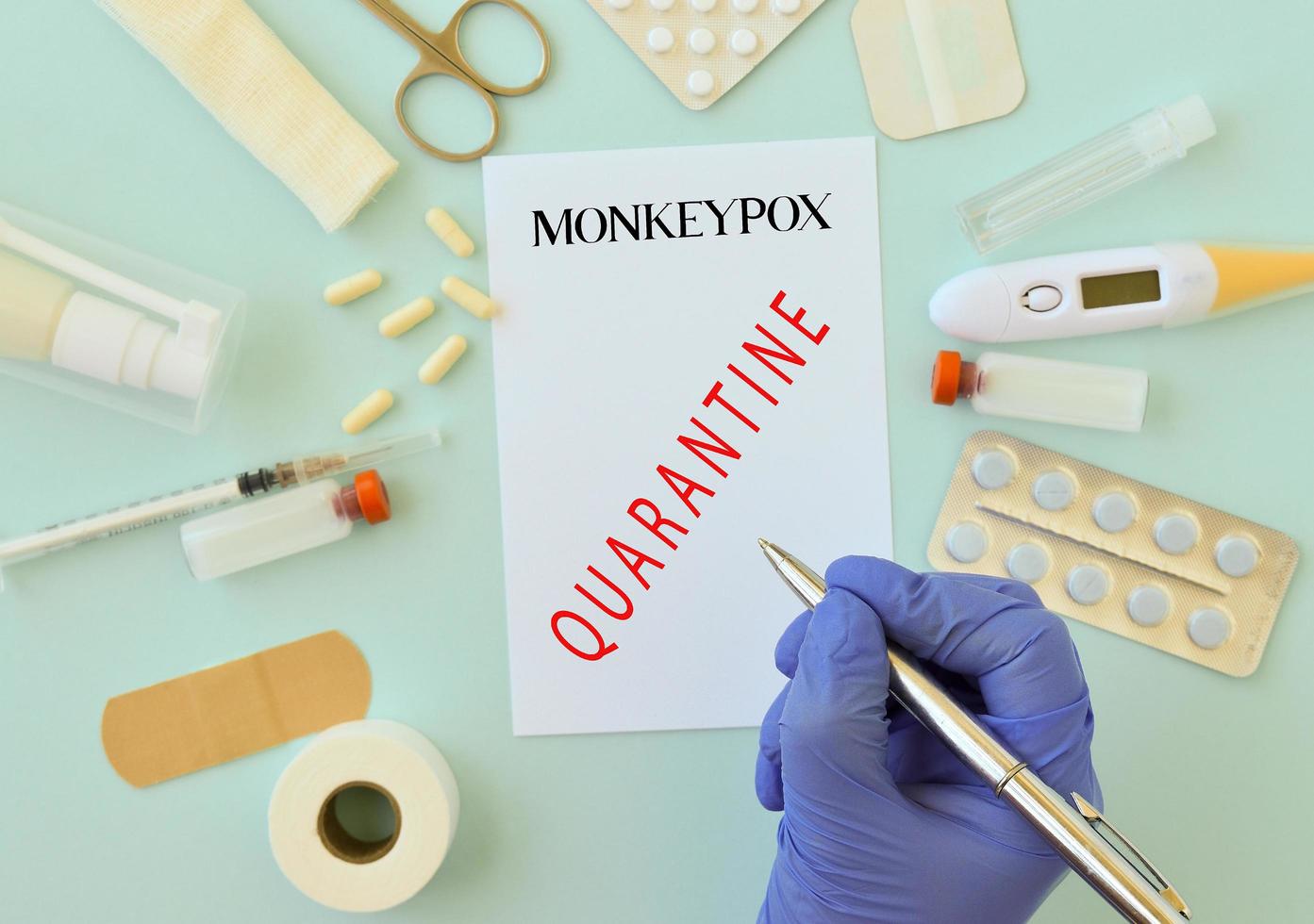 Top view of medical supplies pills, prits.patches, vaccines that lie on a blue background, a doctor's hand in a medical glove holding a pen. Epidemic, quarantine. Healthy concept photo