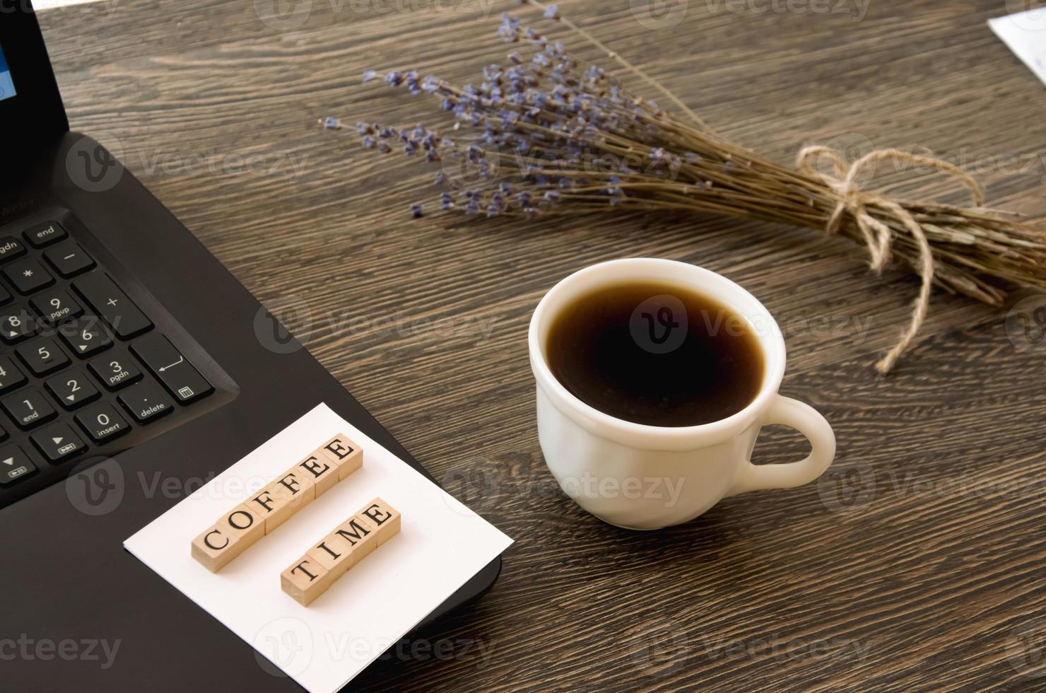 a cup of coffee near the computer and a bouquet of lavender, the inscription coffee time photo