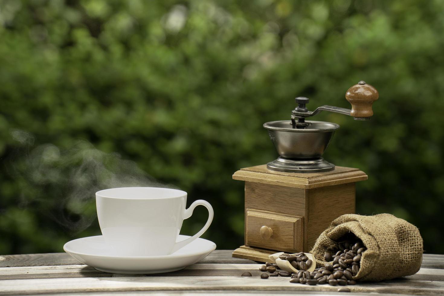 coffee cup with a grinder, Dark Coffee beans on the old wooden floor,  Close up of seeds of coffee in a natural background. photo