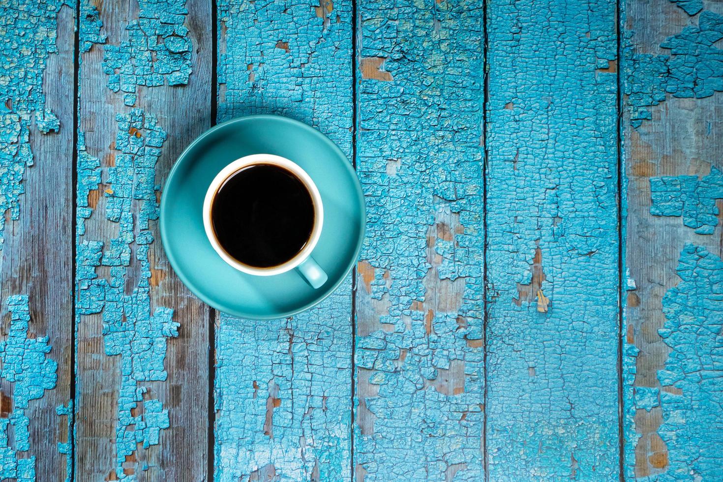 café negro en una taza de cerámica azul en el viejo piso de madera azul foto